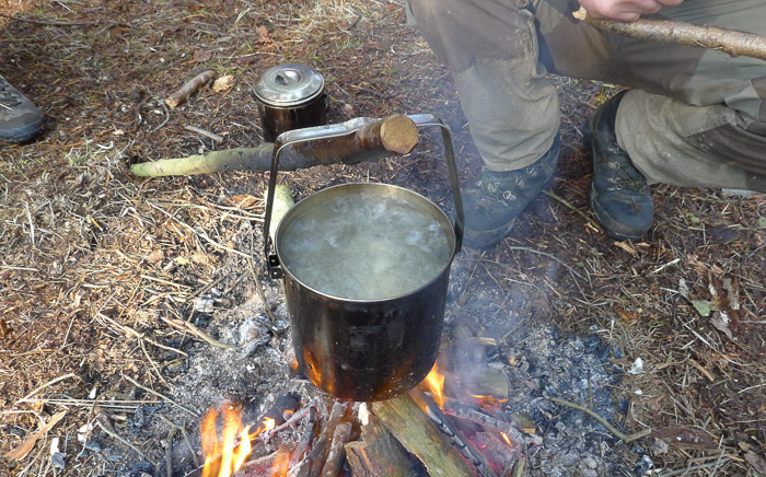 eau non potable en ébullition sur un feu de camp pour la purifier