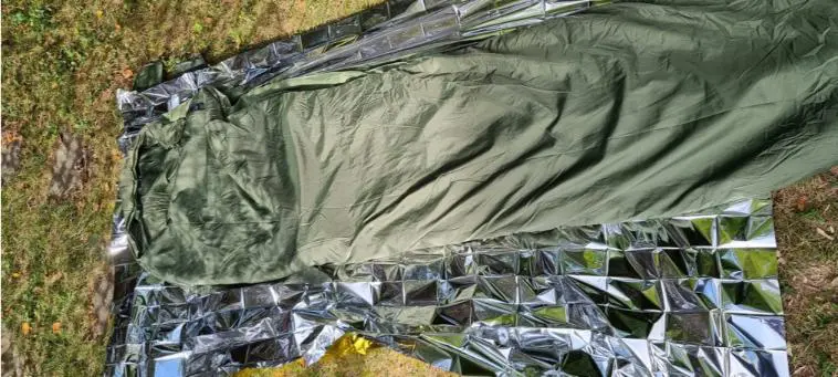 Test matos : le sac de couchage 8 couverture de survie sur le sol